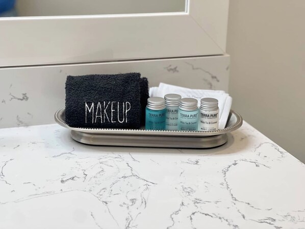 A tray with a black towel labeled "MAKEUP" and three bottles of Terra Pure body wash and lotion on a marble countertop.
