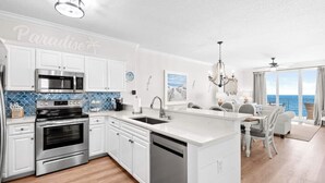 A modern kitchen with white cabinetry, stainless steel appliances, and a blue backsplash.
