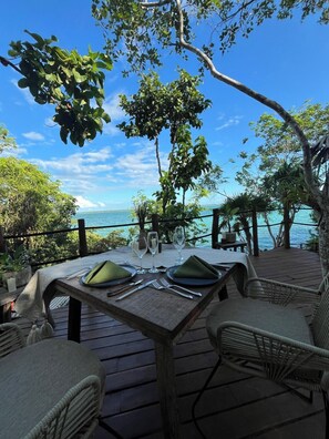 An outdoor dining area with a table set for two, overlooking a body of water. - Naya Bacalar Hotel - Adults Only (Bacalar)