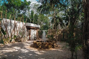 A courtyard with a stone fountain, a rustic building, and lush greenery.