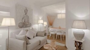 Een minimalistische woonkamer met een bank, een eettafel en een Boeddhabeeld.