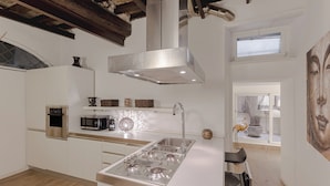 Een moderne keuken met witte kasten, roestvrijstalen apparatuur en een groot raam voor natuurlijk licht.