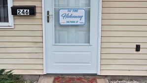 A front door with a 'Welcome' mat, a house number sign, and a sign indicating the property is for Airbnb rental. - Tis’ Time Hideaway. Just a few blocks from beautiful Lake Erie!  (Conneaut)