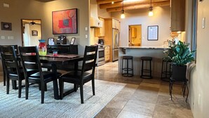 Een moderne keuken met houten balken, een eethoek met een tafel en stoelen, en een bar met krukken.