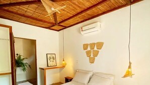 A bedroom with a wooden bed frame, white bedding, a ceiling fan, a wall-mounted air conditioner, and a small bedside table with a lamp. - Pousada alter (Santarém)