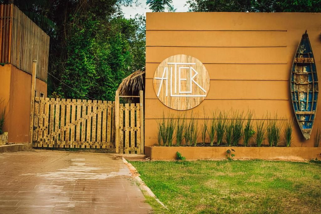 Une entrée d’immeuble avec un portail en bois, un mur orné d’un logo circulaire et une petite décoration en forme de bateau.