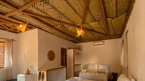 A room with two beds, a small desk, a refrigerator, and a woven ceiling. - Pousada alter (Santarém)