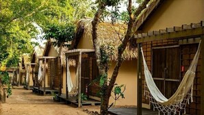 A row of thatched-roof huts with hammocks hanging from the trees. - Pousada alter (Santarém)