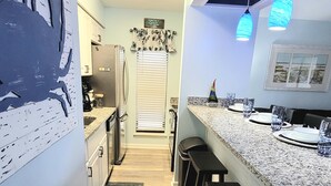 Una cocina moderna con una isla central, taburetes de bar y un refrigerador.