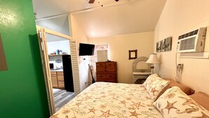 Ein Schlafzimmer mit Bett, Kommode, Schminktisch und Fernseher.
