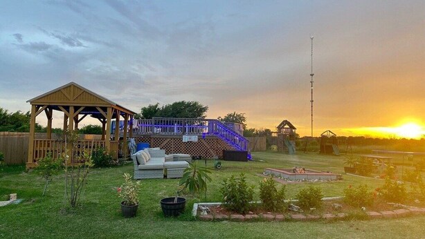 Ein Garten mit einer Holzterrasse, einem Pavillon und einer Terrasse mit Gartenmöbeln.
