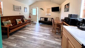 Ein gemütliches Wohnzimmer mit einer braunen Ledersofa, einem Holzesstisch und einem Deckenventilator.