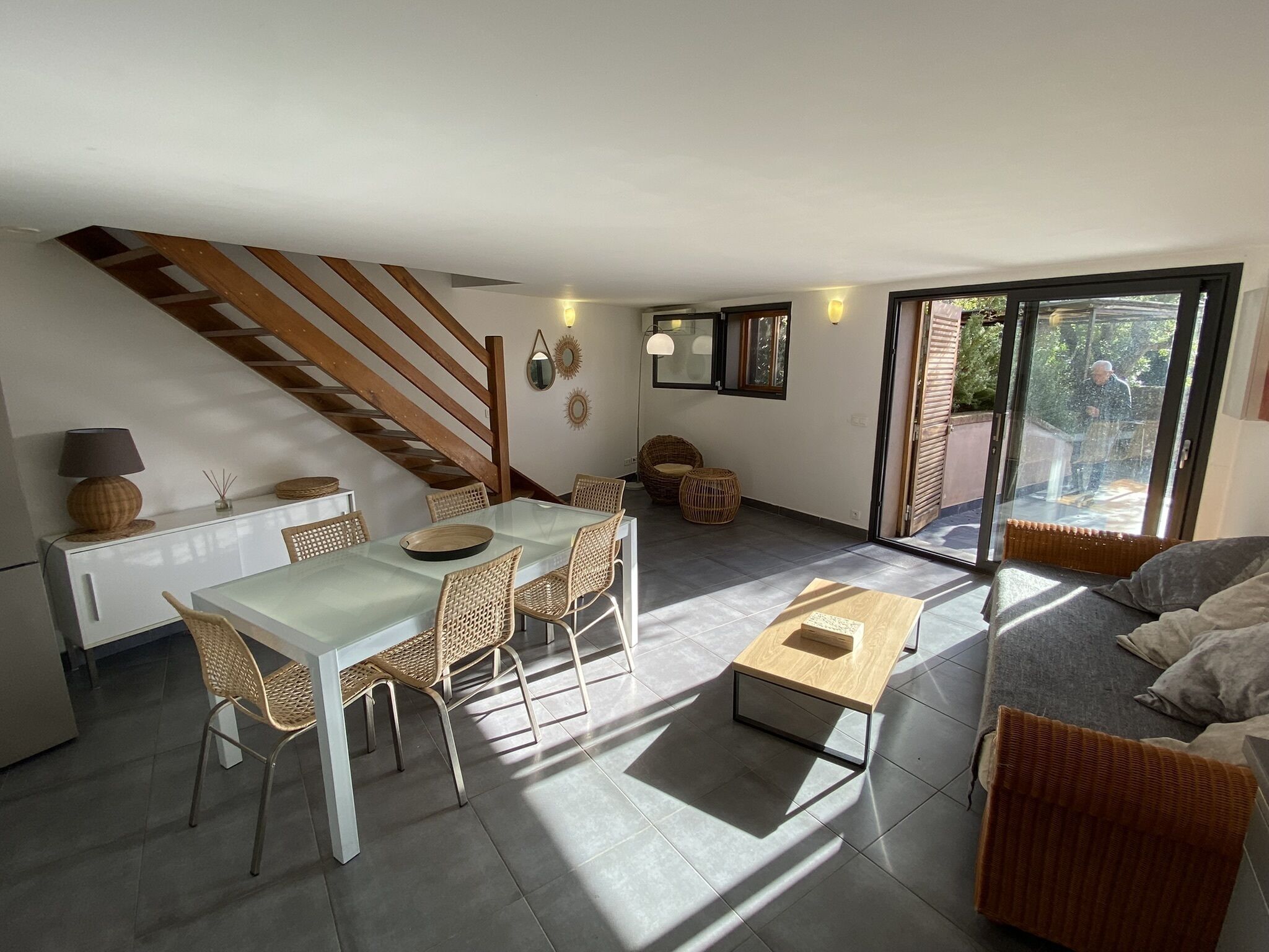 Ein modernes Wohnzimmer mit Essbereich, einer Couch und einer Treppe.