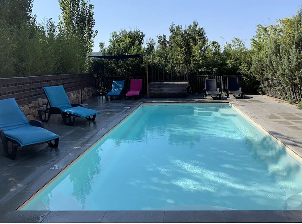 Une piscine rectangulaire entourée de chaises longues bleues et roses.