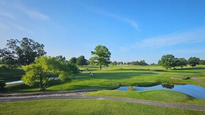 A golf course with a pond, trees, and a clear sky. - Family-Friendly Branson Condo w/ Outdoor Pool! (Branson)