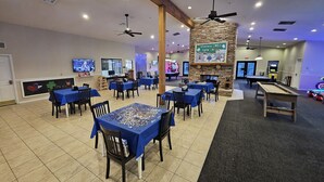 A spacious indoor area with multiple tables and chairs, a pool table, ceiling fans, and a fireplace. - Family-Friendly Branson Condo w/ Outdoor Pool! (Branson)