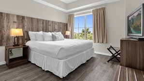 A hotel room with a large bed, two bedside lamps, a TV, and a window with curtains.