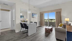 A modern living room with a sofa, a coffee table, and a dining area with a table and chairs.