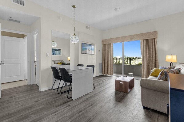 A modern living room with a sofa, a coffee table, and a dining area with a table and chairs.