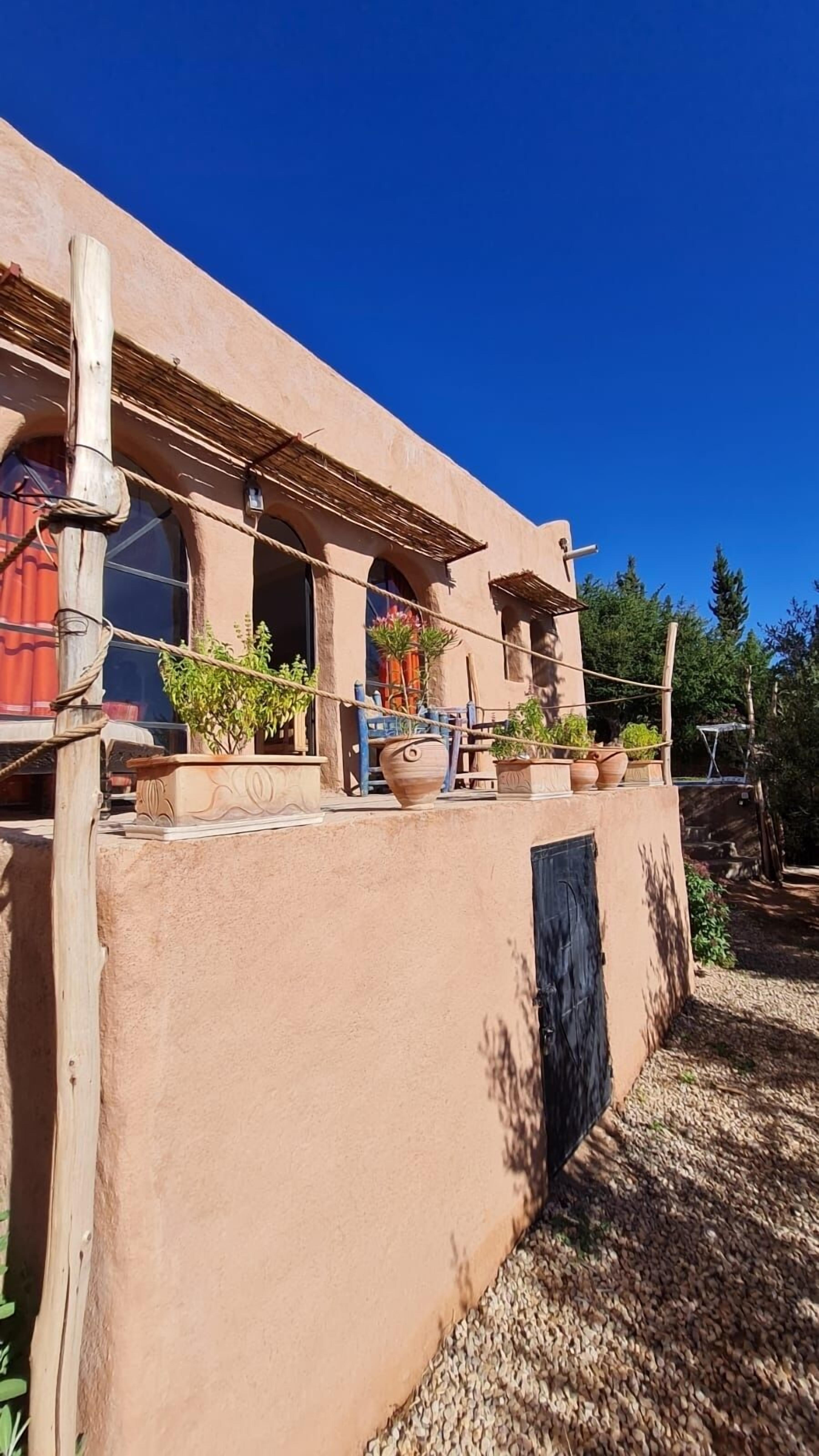 A stucco building with arched windows and a covered porch.