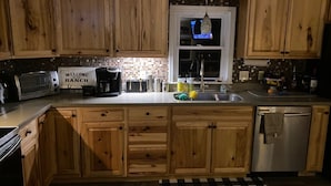 Una cocina con armarios de madera, microondas, cafetera y lavabo.