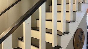 Una escalera con paredes blancas y barandales negros que conduce a un piso superior.
