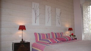 Een slaapkamer met een bed, twee nachtkastjes, een dressoir en wanddecoratie.