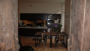 Een moderne keuken met donkere kastjes, een houten eettafel en een hanglamp.