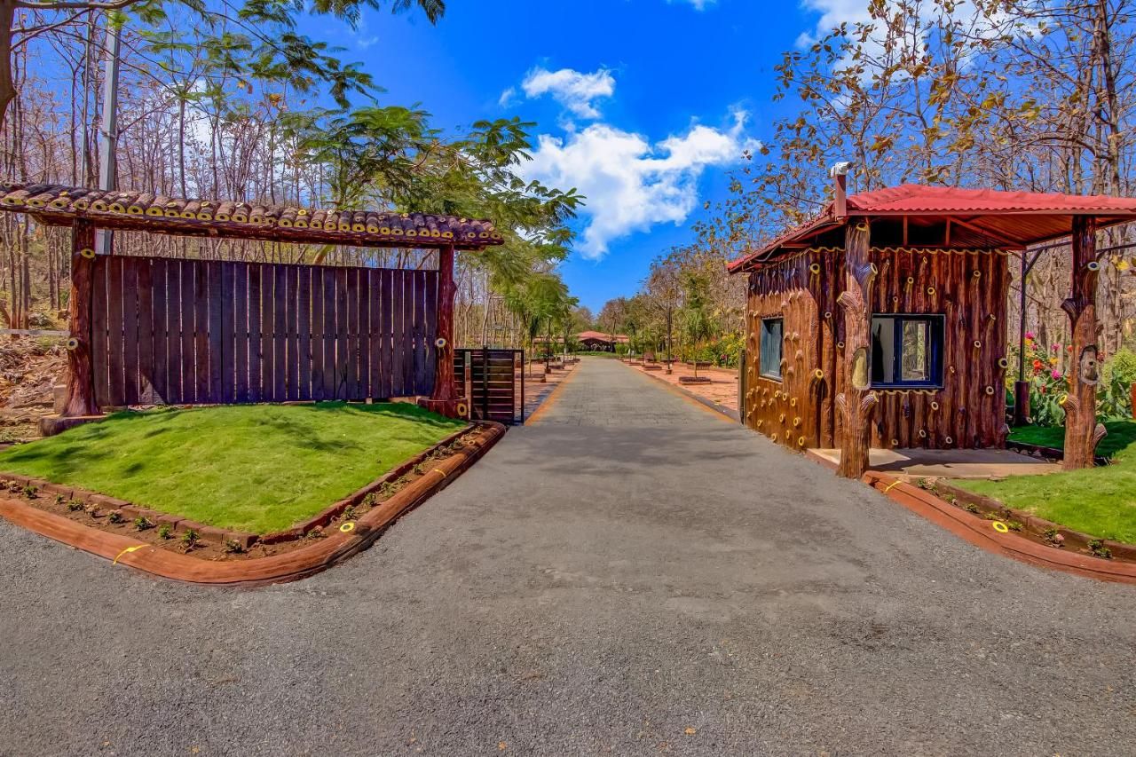 A pathway leading to a rustic wooden building with a red roof, surrounded by trees and a clear sky.