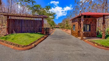 A pathway leading to a rustic wooden building with a red roof, surrounded by trees and a clear sky.