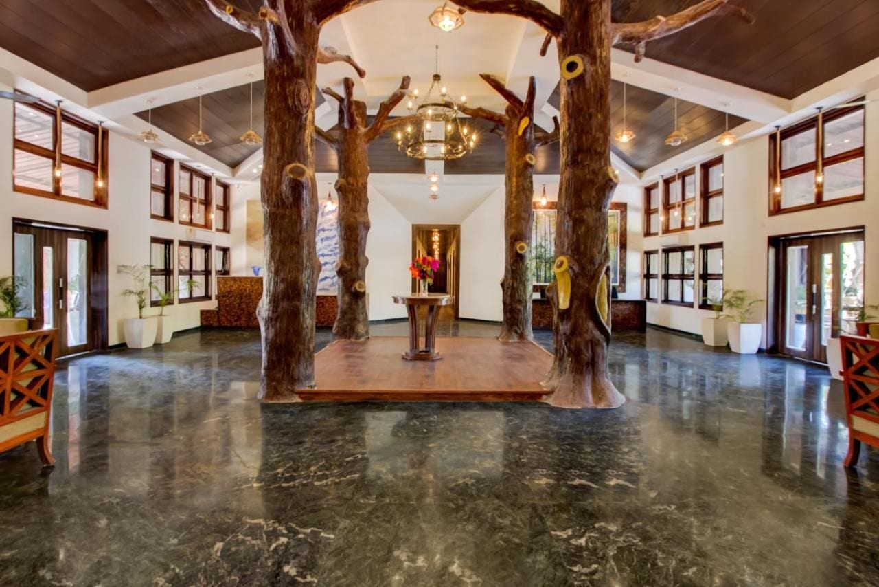 A spacious lobby with a central wooden tree structure, large windows, and a chandelier.
