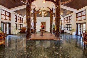 A spacious lobby with a central wooden tree structure, large windows, and a chandelier.