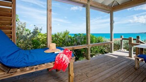 A wooden deck with a blue cushioned bench, a straw hat, and a red cloth.