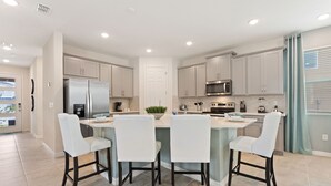 A modern kitchen with a central island, bar stools, and built-in appliances.