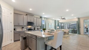 A modern kitchen with a central island, stainless steel appliances, and light-colored cabinetry.