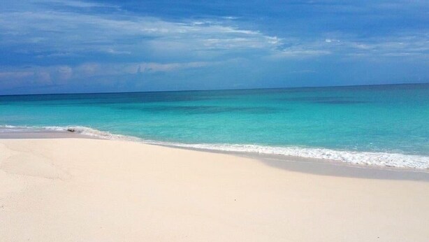 Une plage à l’eau turquoise et au sable blanc.