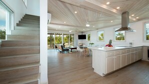 Une cuisine spacieuse dotée d’un grand îlot central, d’un plancher en bois et offrant une vue sur l’extérieur.