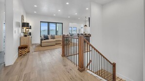 A spacious living area with a wooden staircase, a sofa, and a view of the outdoors.