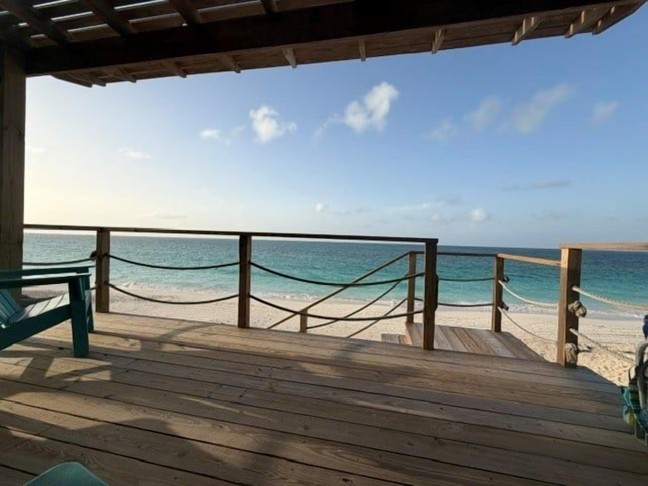 A wooden deck with a view of the beach and ocean.