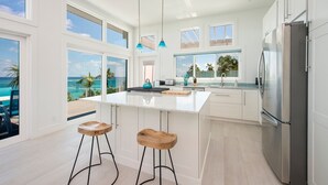 A modern kitchen with large windows, a central island, and a view of the ocean. - Dream House 3 Bedroom Home (North Palmetto Point)