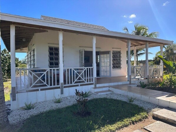 A single-story house with a covered porch, a small garden, and a clear blue sky. - Rocks Retreat 2 Bedroom Home (North Palmetto Point)