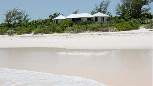 A beachfront property with a white house, sandy beach, and surrounding vegetation. - Provender 5 Bedroom Home (Savannah Sound)