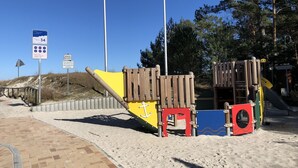 A beachside playground with a wooden play structure, a sandy path, and a sign indicating a water reservoir. - Apartment Seestern Prerow/parking lot, 2 bicycles, bed linen/towels incl. (Prerow)