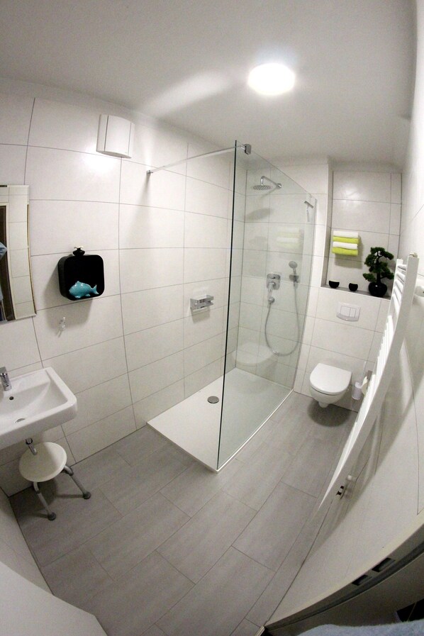 A modern bathroom with a glass-enclosed shower, a white sink, and a toilet. - Apartment Seestern Prerow/parking lot, 2 bicycles, bed linen/towels incl. (Prerow)