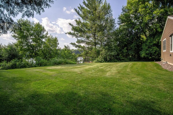 A well-maintained lawn with a wooden deck and a house in the background.