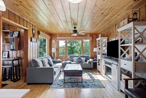 A cozy living room with a sofa set, a coffee table, and a TV on a wooden wall.