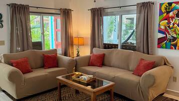 A living room with a sofa, a coffee table, patterned rugs, and a ceiling fan.
