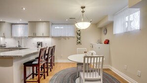 Une cuisine moderne avec un îlot central, des chaises en bois, une table de salle à manger ronde et un tapis à motifs.