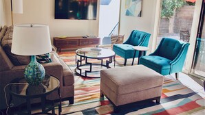 Una sala de estar con sofá, reposapiés, dos sillones, una mesa de centro y una lámpara.