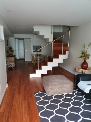 A modern interior with a wooden staircase, a dining area, and a living space with a patterned rug. - Station House (Guimarães)